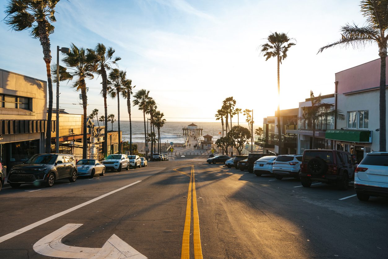 View to the Pier in Manhattan Beach at sunset, street with cars and palm trees lined on both sides